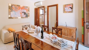 Un comedor con mesa de madera, sillas, un sofá y obras de arte en las paredes.