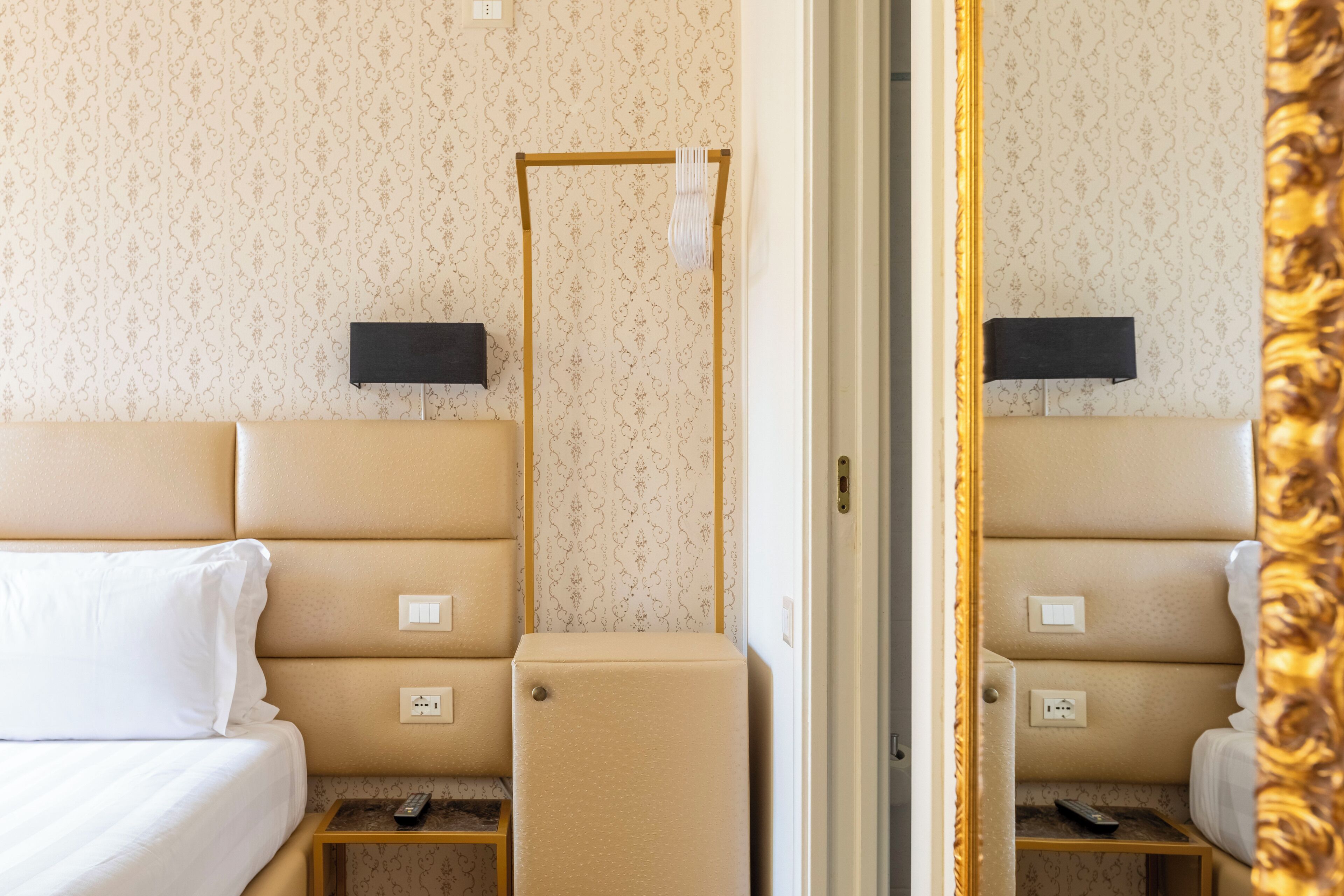Une chambre d’hôtel avec un lit, une table de chevet et un petit meuble.