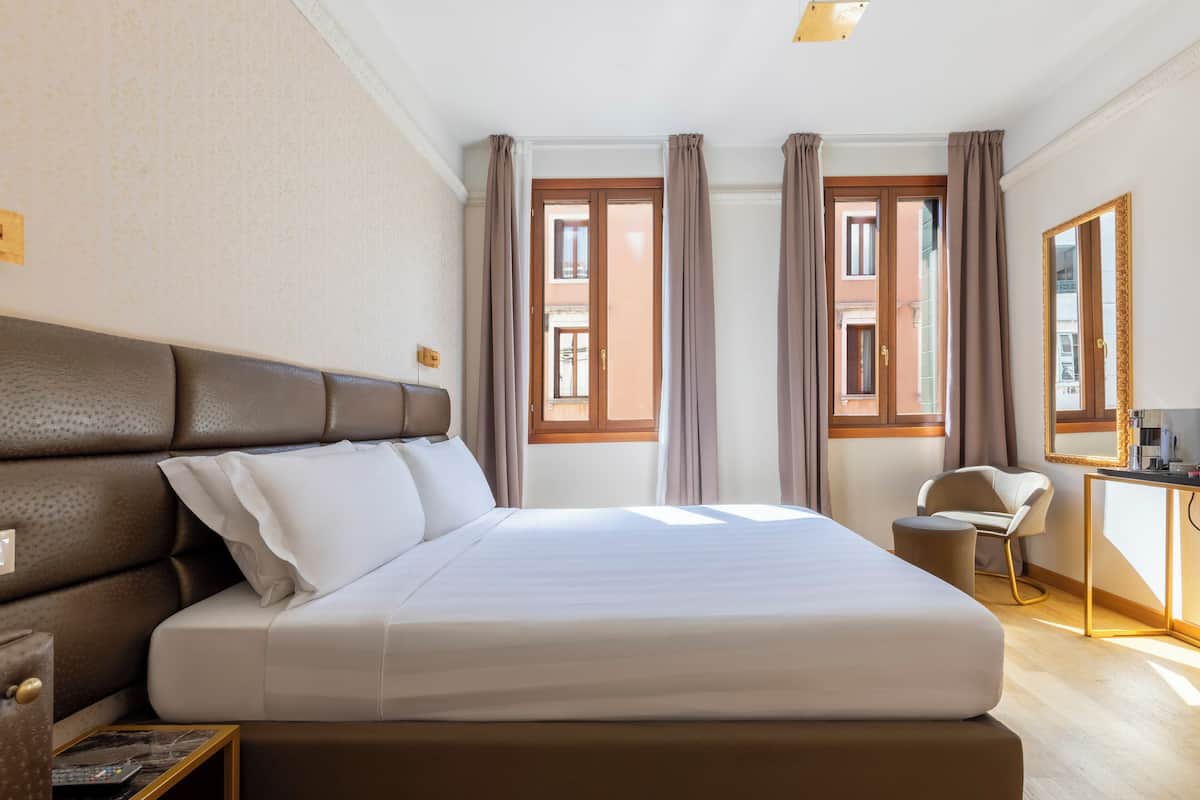 A hotel room with a large bed, a desk, and a chair.