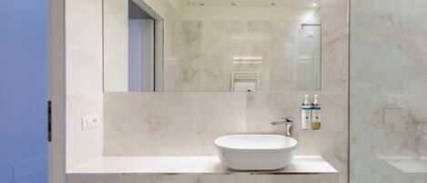 A modern bathroom with a large mirror, a vessel sink, and a glass shower enclosure.