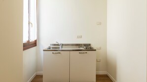A small kitchenette with a sink, stove, and cabinets. - Numa Venice Palazzo Orseolo (Venice)