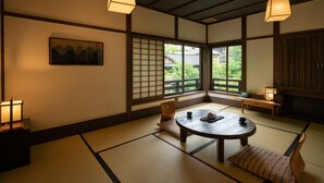 Une pièce de style japonais traditionnel, avec un sol recouvert de tatamis, une table basse avec des coussins et des portes coulissantes.