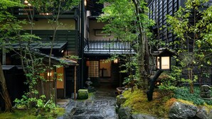 Un bâtiment de style japonais traditionnel, avec un chemin de pierre menant à une entrée en bois.