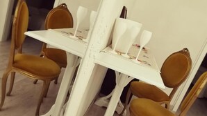 A dining table with four chairs, each with a gold cushion. - Guest House Urbana (Rome)