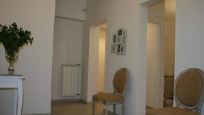 A room with two chairs, a radiator, and a small table with a vase of flowers. - Guest House Urbana (Rome)