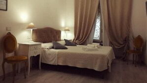 A bedroom with a bed, two bedside tables, a desk, two chairs, and a window with curtains. - Guest House Urbana (Rome)