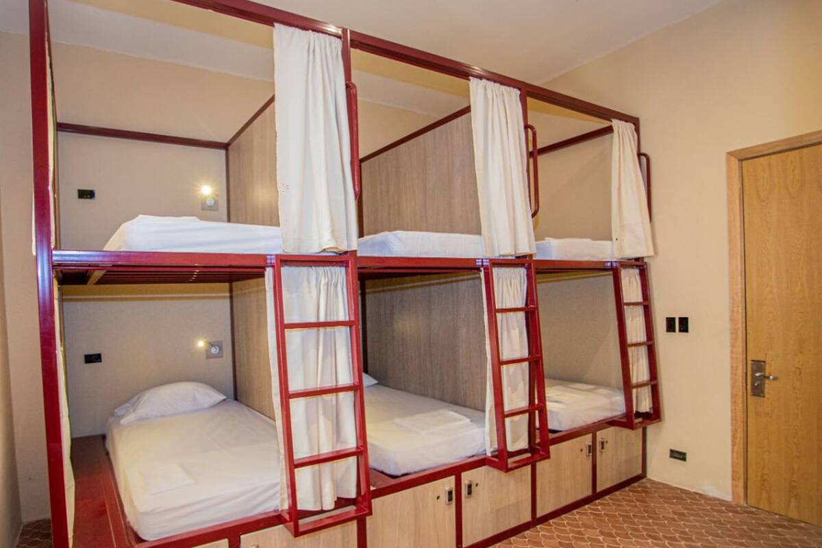 Ein Zimmer mit zwei Etagenbetten, jeweils mit einer Leiter und einem Vorhang.