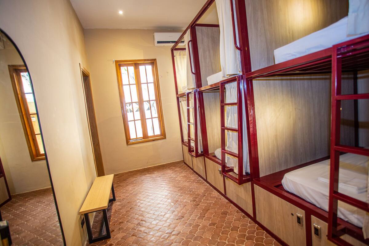 Ein Zimmer mit Etagenbetten, einer Bank und einem Fenster.