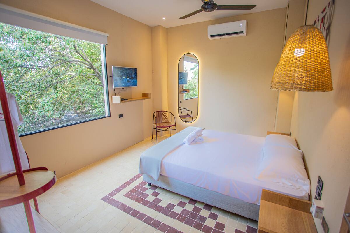 Ein Schlafzimmer mit einem Bett, einem Sessel, einem Fenster und einem Deckenventilator.