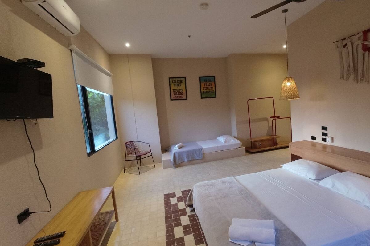 Ein Hotelzimmer mit einem Bett, einem Schreibtisch mit Stuhl, einem Fernseher und einem Fenster.