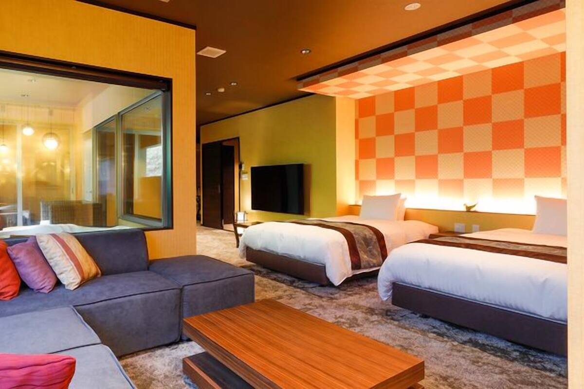 Une chambre d’hôtel avec un canapé, deux lits, une télévision et une grande fenêtre.