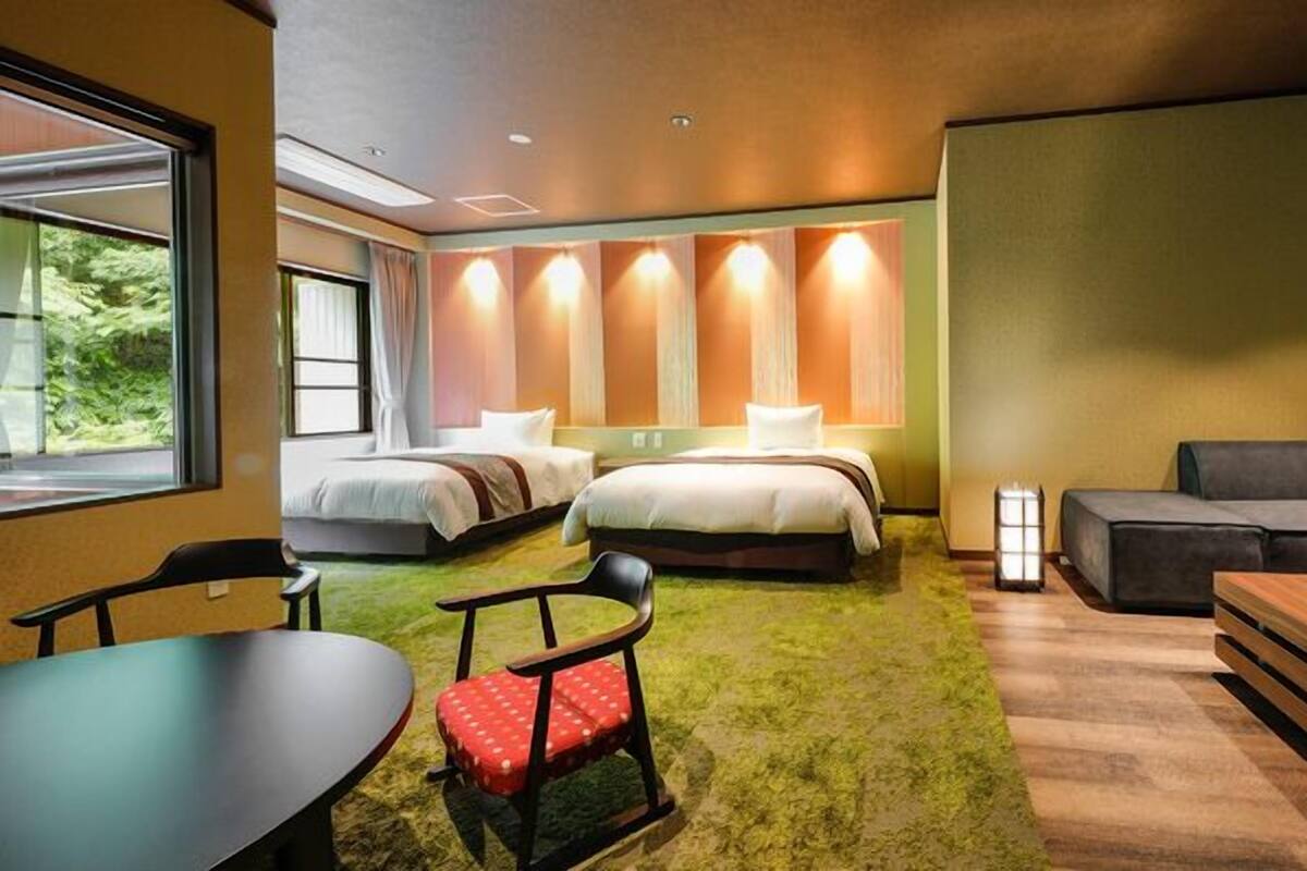 Une chambre d’hôtel avec deux lits, un canapé, une table et une chaise.