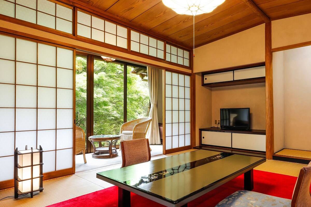 Une pièce de style japonais traditionnel, avec un sol recouvert de tatamis, une table basse et des portes coulissantes.