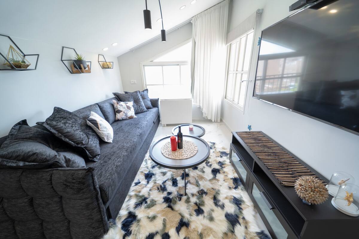 Elite appartement | Woonruimte | Een 65-inch flatscreentelevisie met satellietzenders en smart-tv