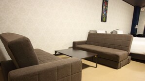 A room with a sofa, a chair, and a small table. - White Beachi inn Ishikawa (Uruma)