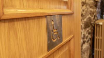 Una puerta de madera con el símbolo de accesibilidad para personas con discapacidad y una placa de metal.