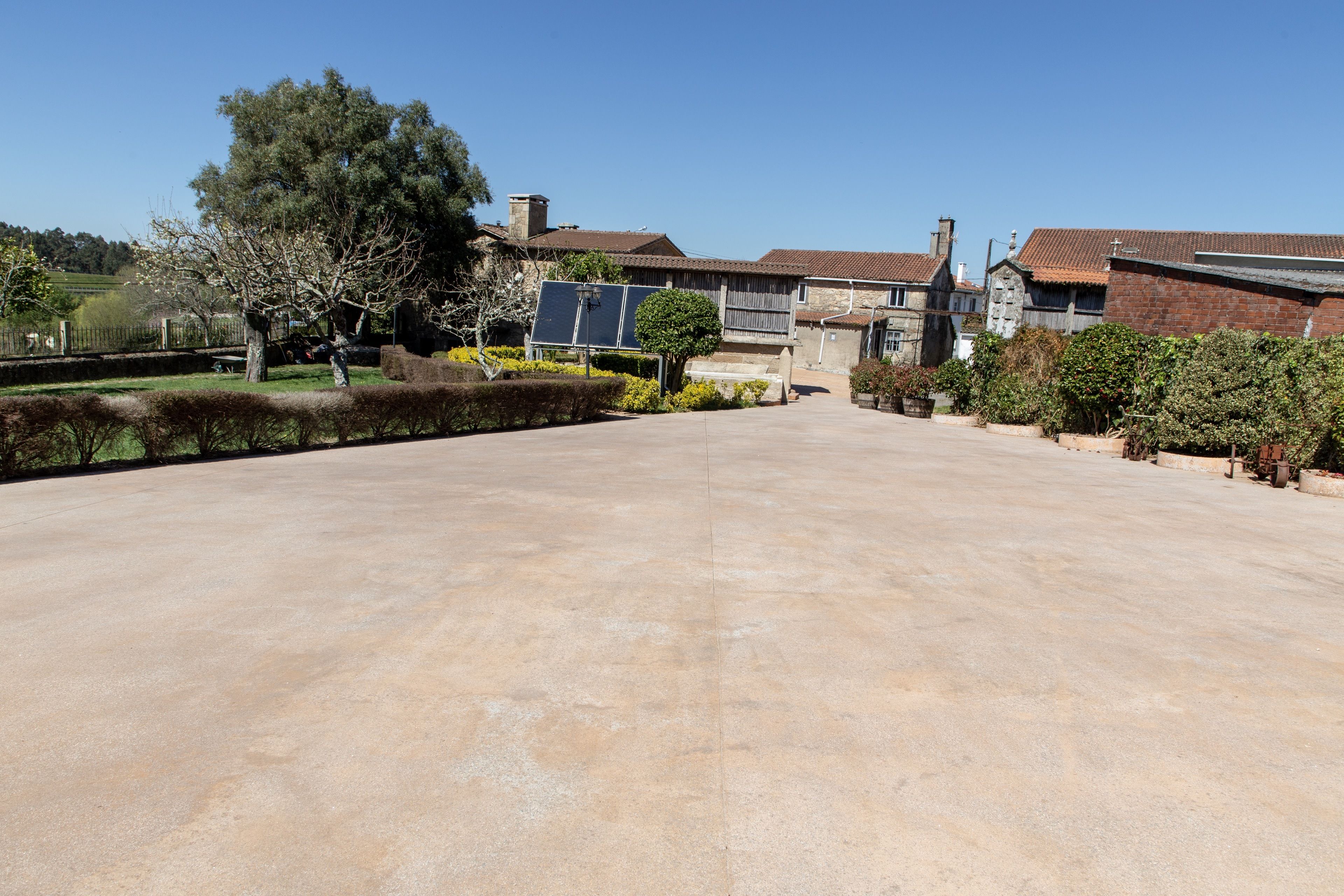 A spacious courtyard with a paved area, surrounded by traditional buildings with tiled roofs and stone walls.
