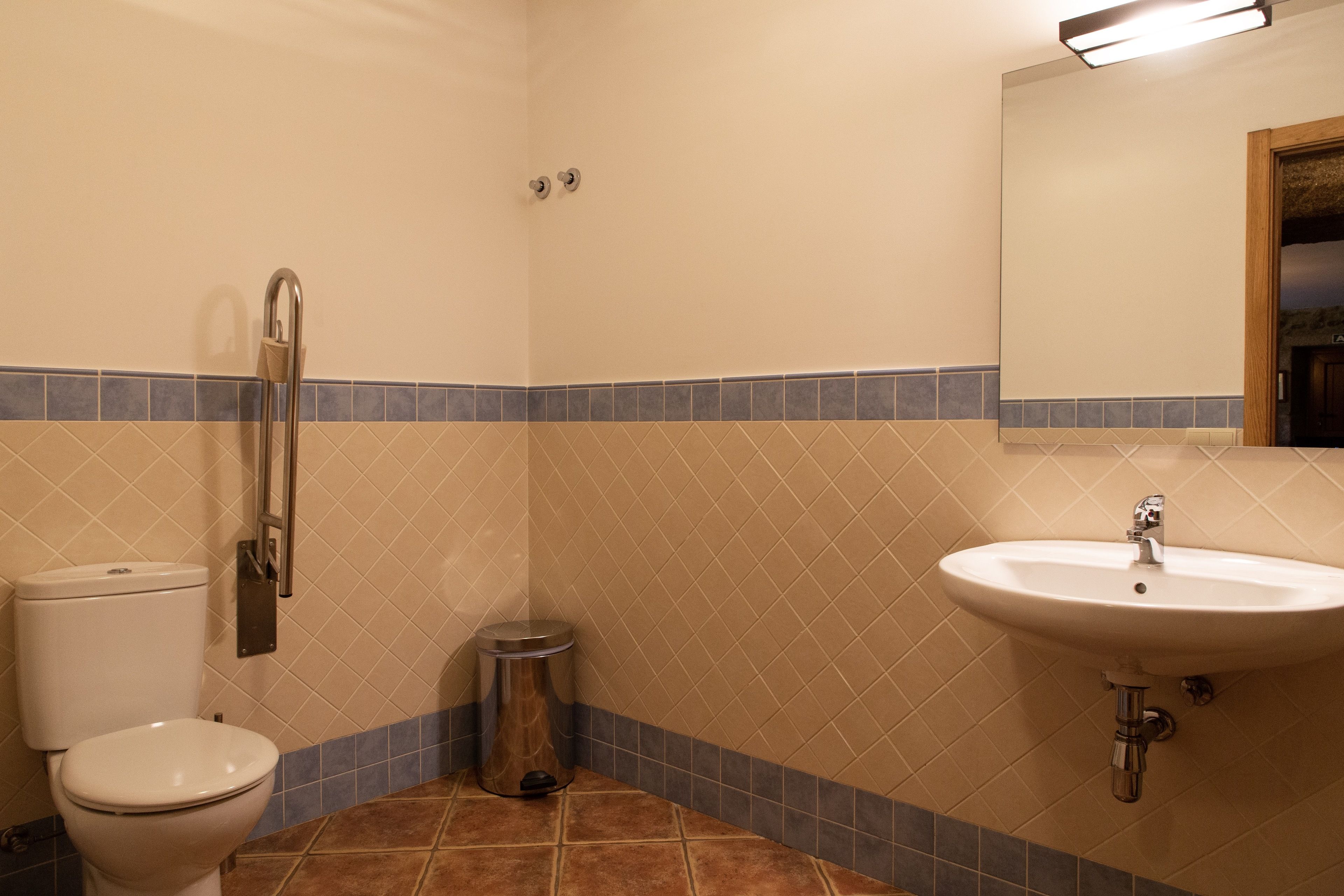 Ein Badezimmer mit Toilette, Waschbecken, Spiegel und Mülleimer.