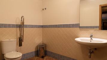 Ein Badezimmer mit Toilette, Waschbecken, Spiegel und Mülleimer.