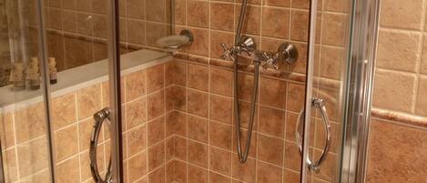 Cabina de ducha con paredes de vidrio, cabezal de ducha de mano y rociador de mano.