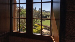 Una ventana con vistas a un jardín y un edificio con tejado tradicional.