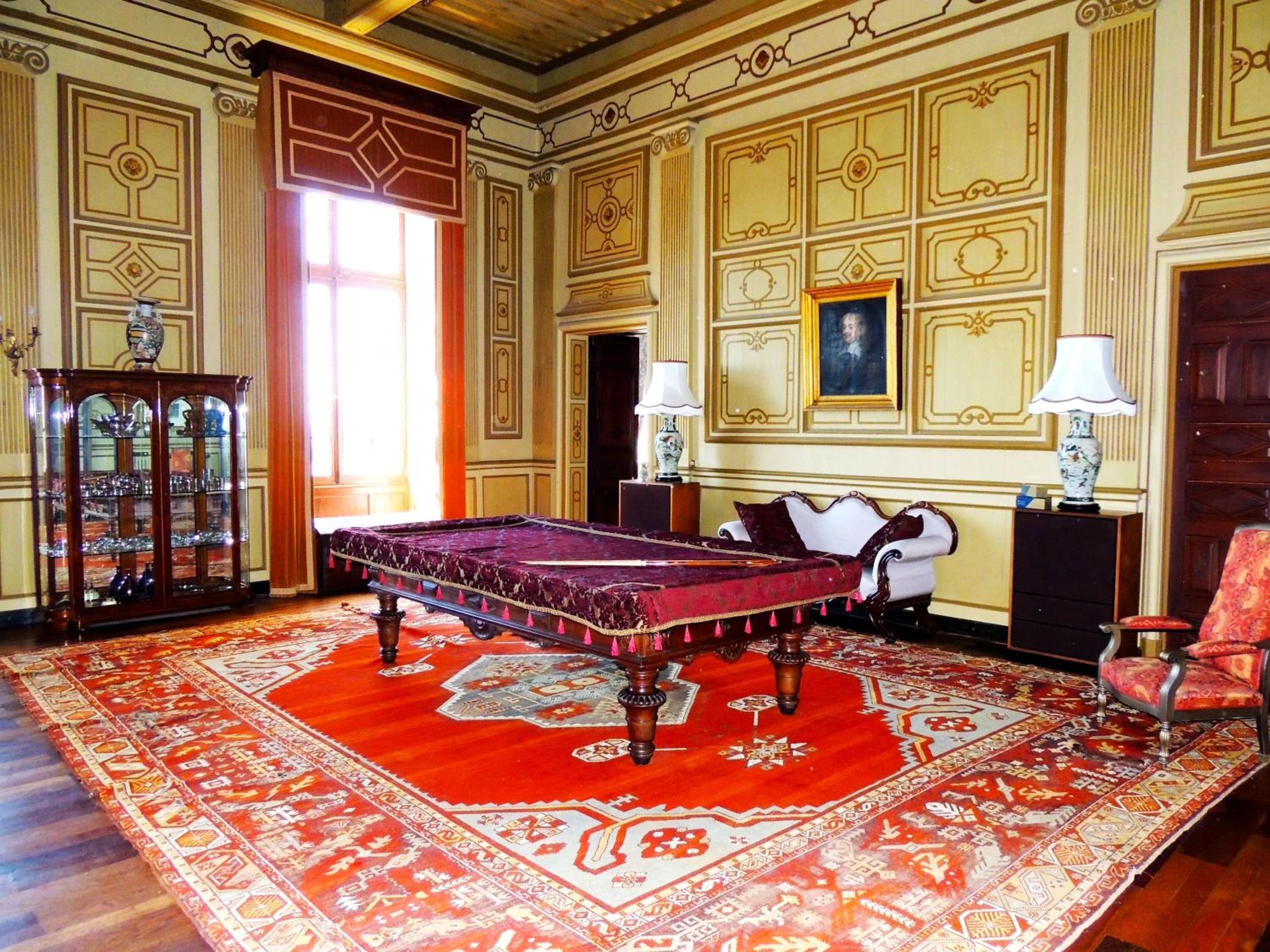 A room with a large bed, a wooden cabinet, and a red patterned rug.