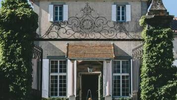 A stately building with a symmetrical facade, a central entrance with a decorative arch, and a fountain in the courtyard.