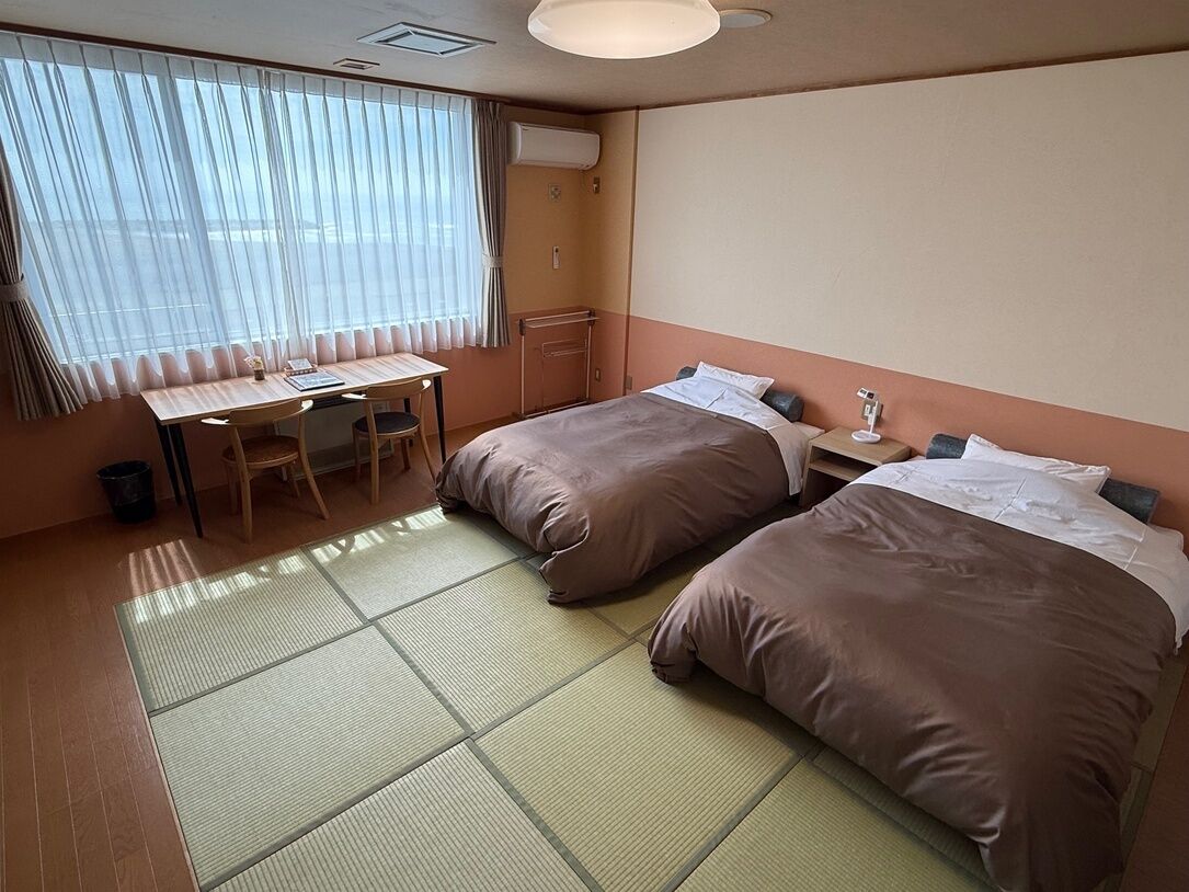 Una habitación de hotel con dos camas, un escritorio y una silla.
