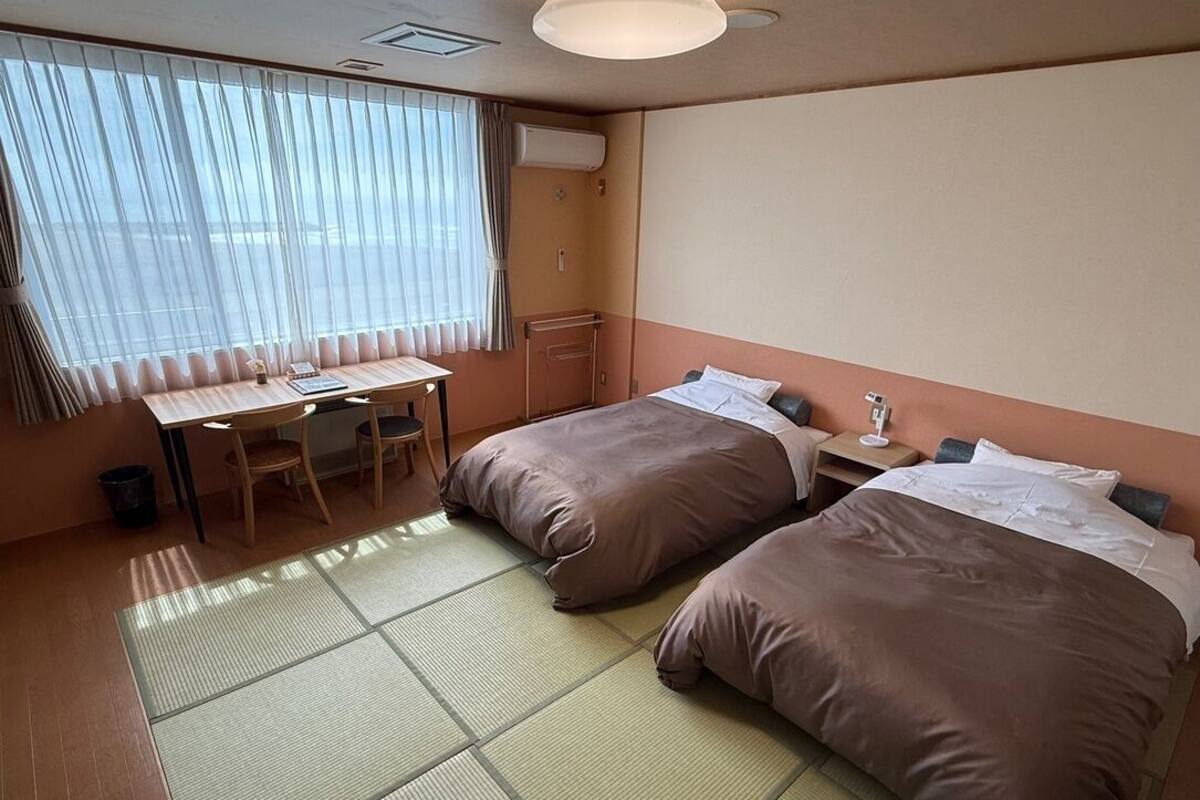 Una habitación de hotel con dos camas, un escritorio y una silla.