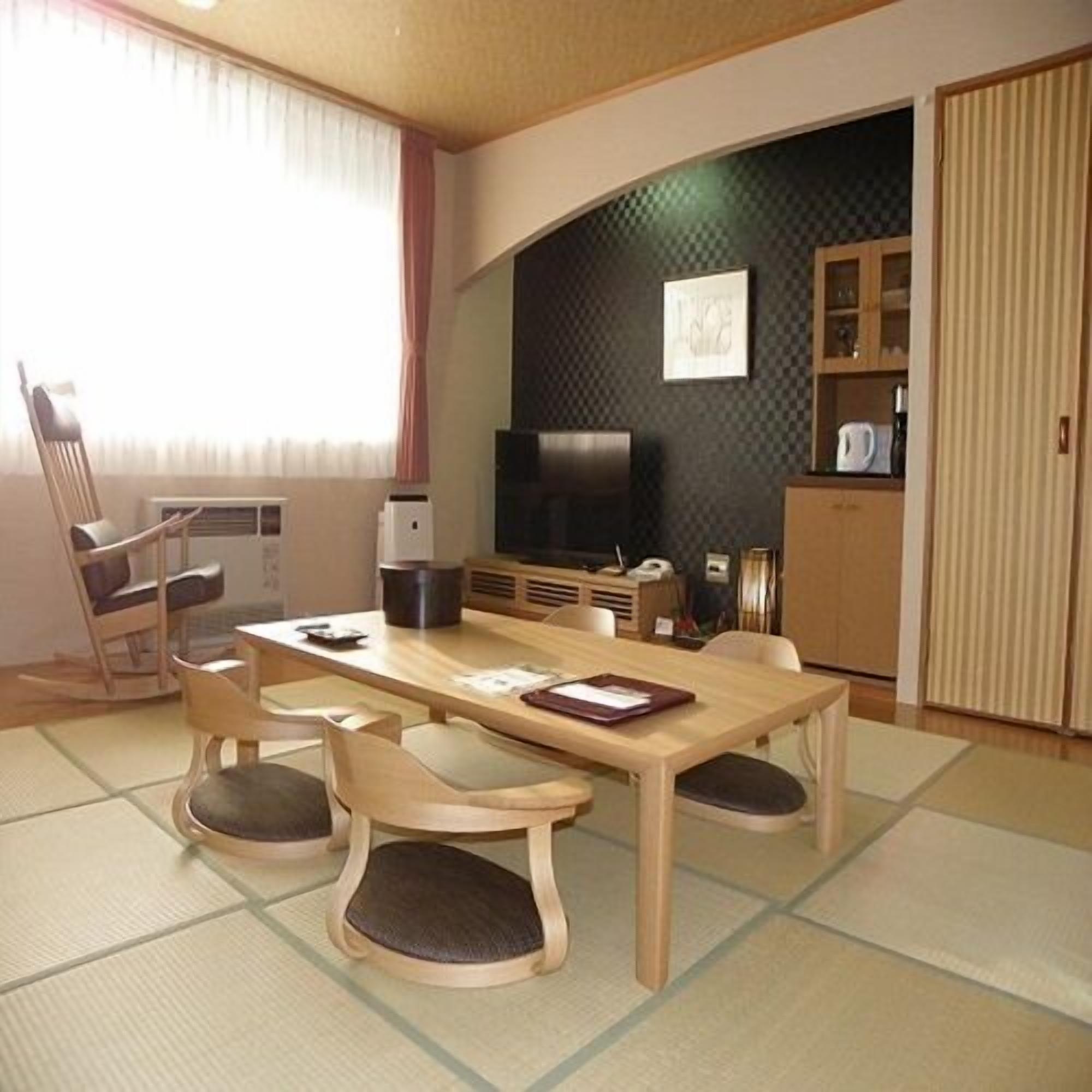 A room with a dining table, chairs, a television, and a cabinet.