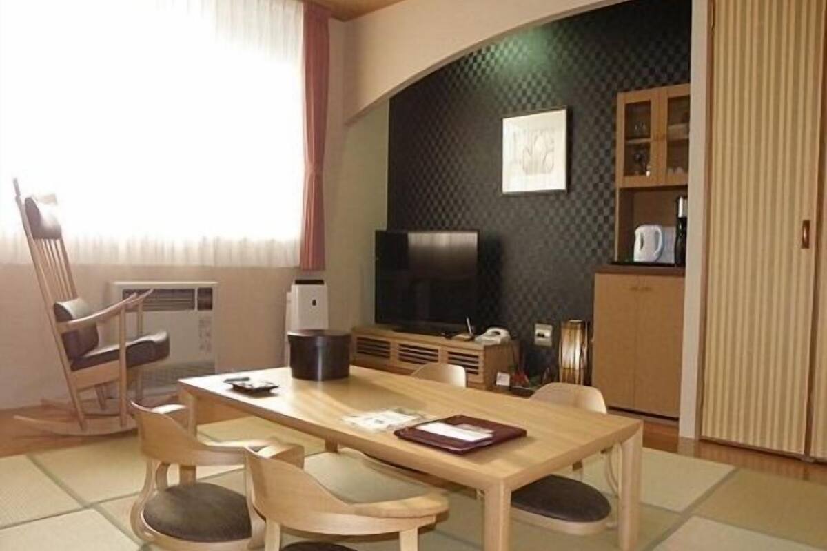 Una habitación con una mesa de comedor, sillas, un televisor y un armario.