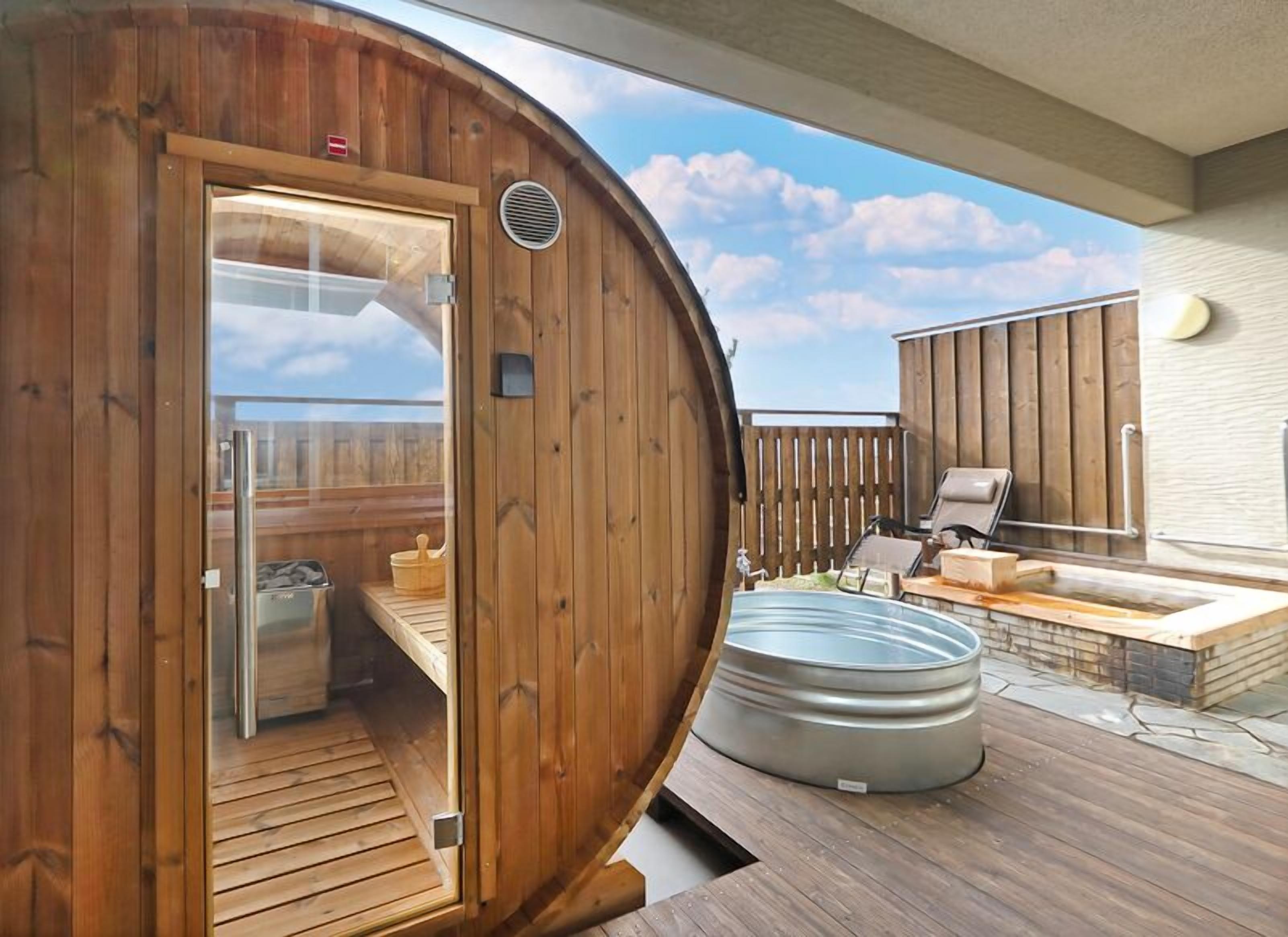 Una sauna de madera con puerta de vidrio, un jacuzzi y una terraza con asientos exteriores.