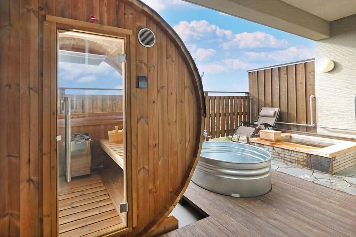 Una sauna de madera con puerta de vidrio, un jacuzzi y una terraza con asientos exteriores.