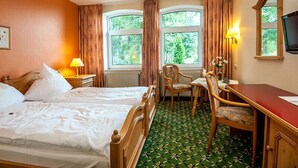 A hotel room with two beds, a desk, a chair, a TV, and large windows with curtains. - Zur Nordseite (Ritterhude)