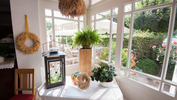 A room with a table, a chair, a hanging wreath, a lantern, and a potted plant. - Zur Nordseite (Ritterhude)