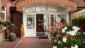 A traditional building with a brick facade, a curved roof, and a welcoming entrance with a wooden sign. - Zur Nordseite (Ritterhude)