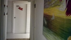 Un pasillo con una puerta que indica el número 205, un cuadro de un paisaje y un piso de baldosas.