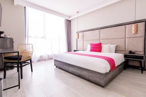 Une chambre d’hôtel moderne, dotée d’un grand lit, d’un bureau et d’une chaise.