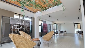 Interior espaçoso e moderno com cadeiras de vime, uma grande pintura abstrata e um jardim vertical.