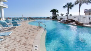 A pool area with lounge chairs, a pool with a waterfall feature, and a view of the ocean. - 5 Pools, 2 heated indoor. 3 hot tubs, movie theater, Starbucks and bar and grill (Panama City Beach)