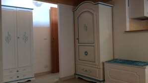 Um quarto com teto de madeira, armários brancos com detalhes em azul e piso de azulejos.