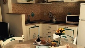 Uma área de refeições com uma mesa posta para dois, um prato de comida, um vaso com flores e uma bandeja decorativa.