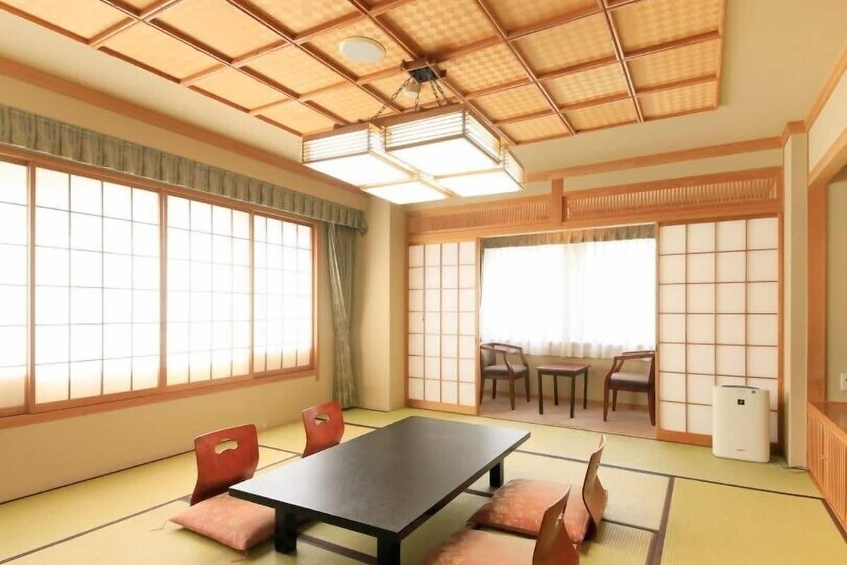 A tatami mat room with a low table, chairs, and sliding doors.