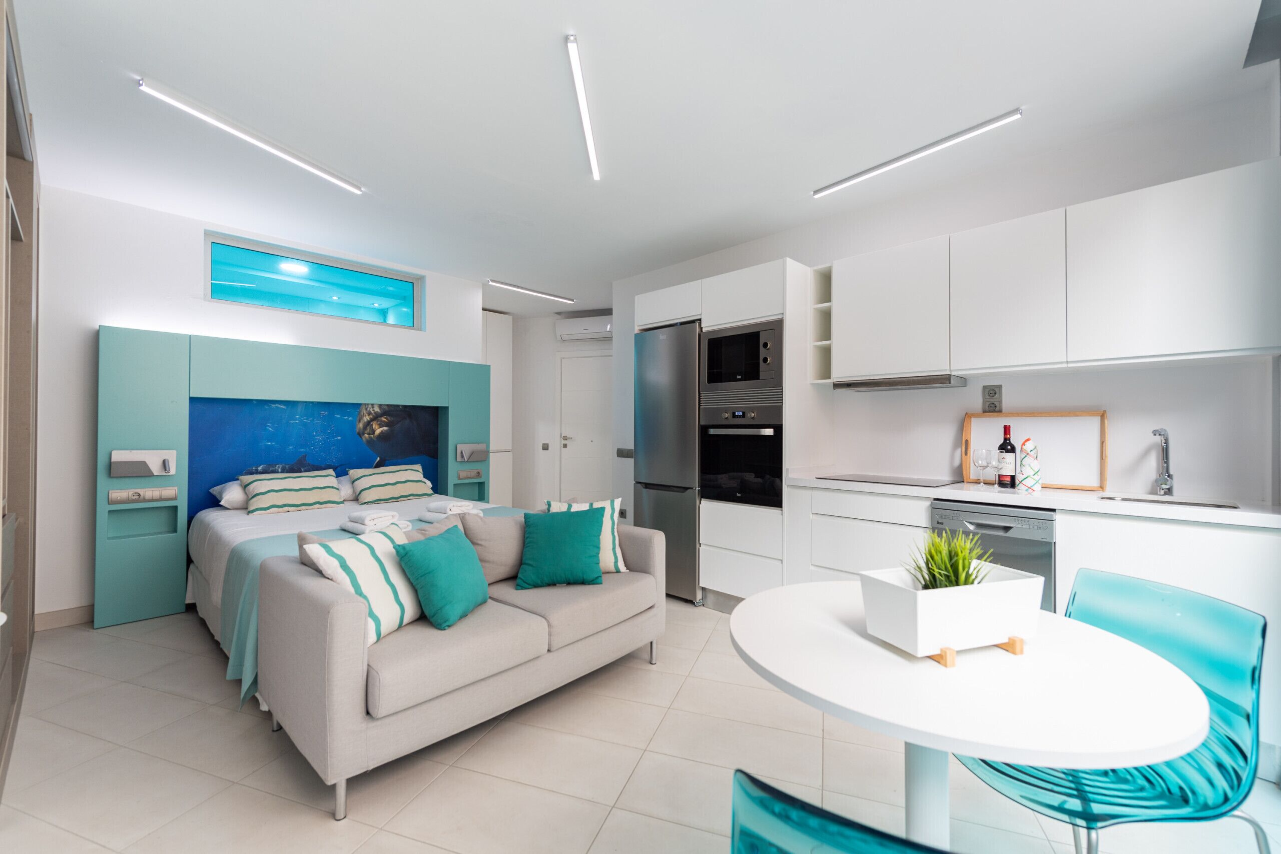 A modern apartment with a kitchenette, a dining area, and a bedroom.