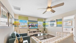 Un salon moderne avec un canapé, un téléviseur et un ventilateur de plafond.