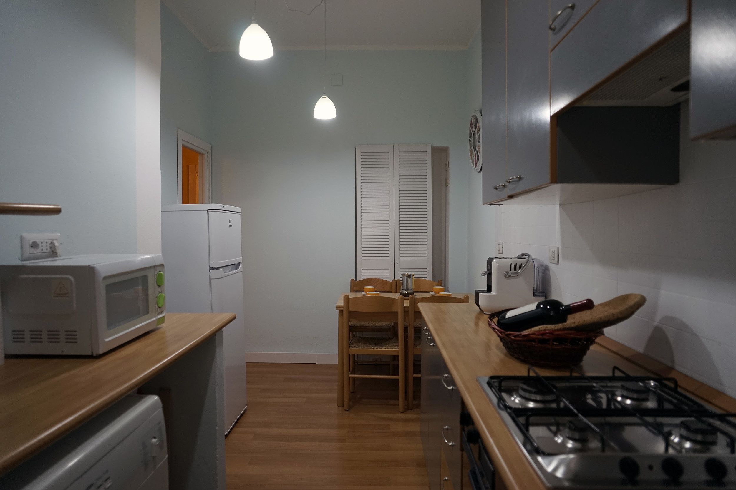 A compact kitchen with a microwave, refrigerator, stove, and wooden dining table.