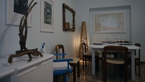 A dining area with a table set for four, chairs, a decorative mirror, and framed artwork on the walls. - Casa Cappone (Alghero)