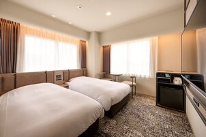 A hotel room with two beds, a small table, a TV, and a coffee maker.