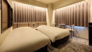 Une chambre d’hôtel avec deux lits, une petite table et une chaise.