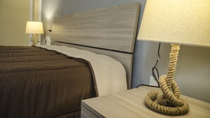 A neatly made bed with a brown comforter, a wooden headboard, and a bedside lamp with a rope base. - Casa Barracuda (Alghero)
